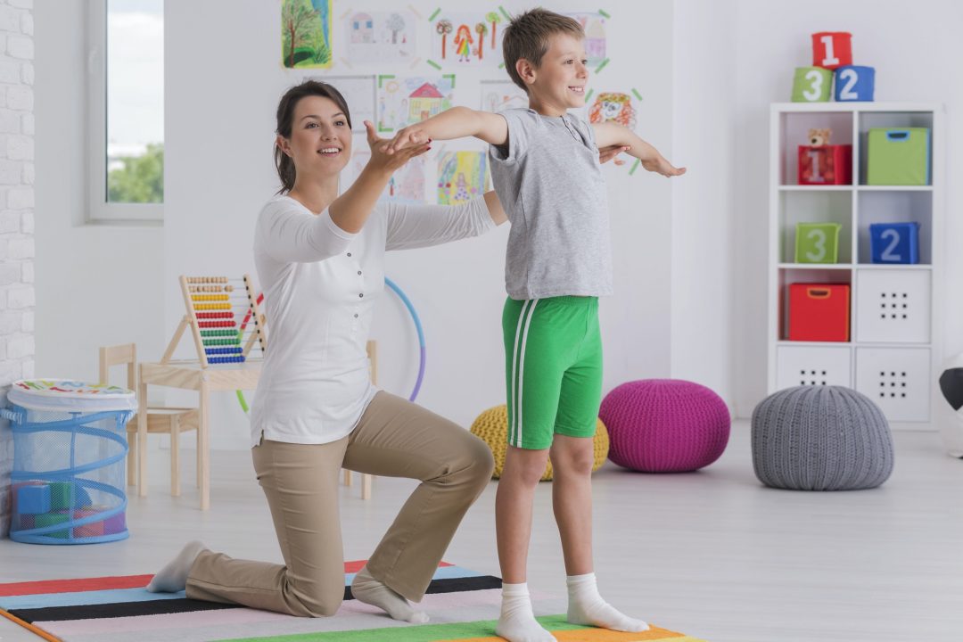 Physiotherapist exercising with a school-boy